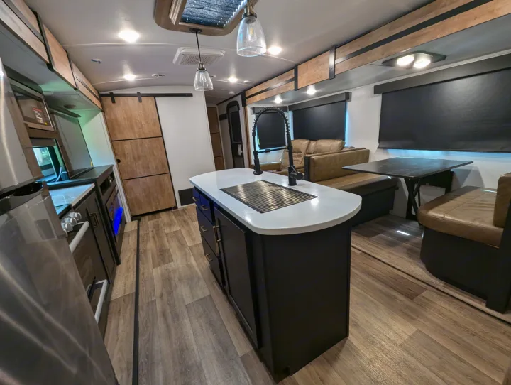 This modern RV rental boasts a full kitchen island, cozy dinette, and comfortable lounge area, ready for adventure.. Keystone RV Outback 2022
