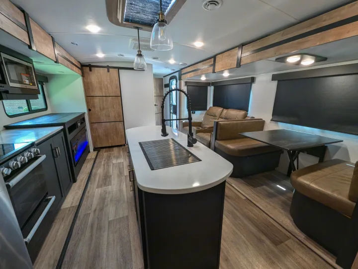 Spacious RV rental interior with a modern kitchen island, stove, cozy recliners, and dinette. Ideal for your travels!. Keystone RV Outback 2022