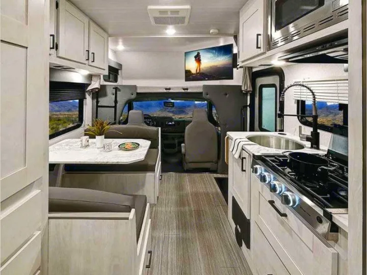 Spacious RV rental interior featuring a modern kitchen, dinette, and scenic desert views for comfortable travel.. Entrada East to West 2024