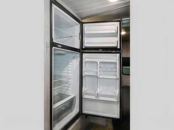 Clean, open RV rental refrigerator. Empty freezer and fridge compartments, ready for your trip.. Entrada East to West 2024