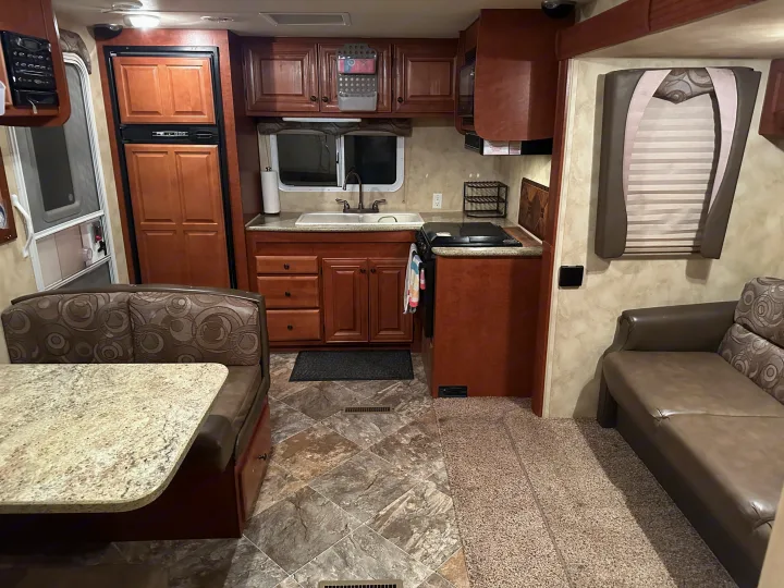 Spacious RV rental interior: well-equipped kitchen, cozy dining booth, and comfortable lounge area with varied flooring.. Northwood Mfg Arctic Fox 2013