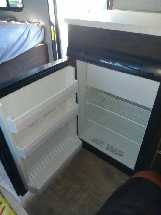 RV rental: The interior shows an open Dometic refrigerator with shelves. A bed is visible in the background of this camper.. Pioneer Trail Blazer 2020