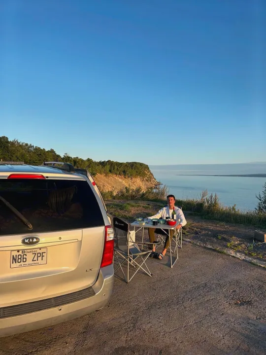 Enjoying a sunset meal at a scenic overlook by a Kia minivan, a perfect spot for an RV rental.. KIA SEDONNA 2008