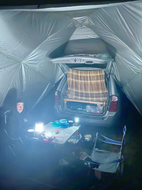 Cozy car camping setup inside a tent with a trunk bed and illuminated dining. A budget-friendly mobile camp, less than an rv rental.. KIA SEDONNA 2008