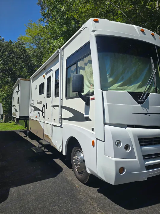This large white RV rental, with slide-outs extended, is parked on asphalt under a blue sky, ready for adventure.. Winnebago Sightseer 2008