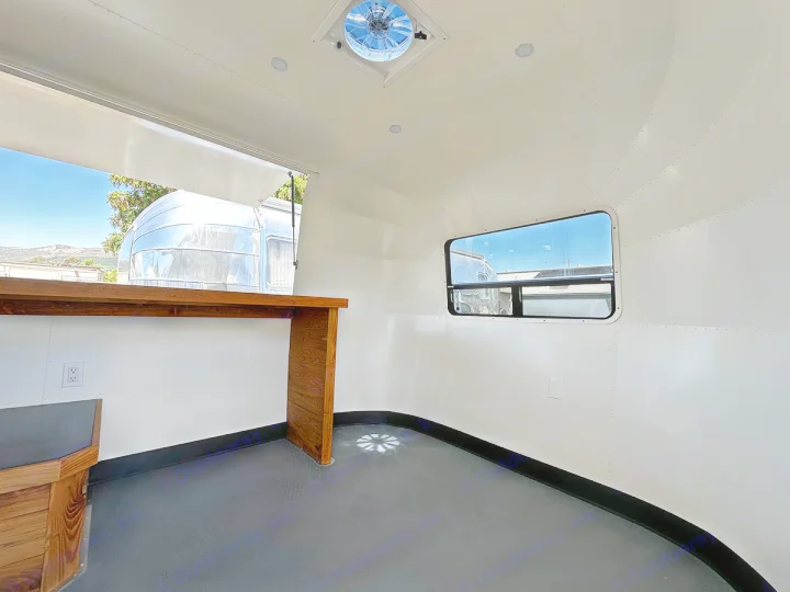 Clean, bright RV rental interior with a wide serving window for a mobile business setup, featuring a wooden counter.. Airstream Custom 2006