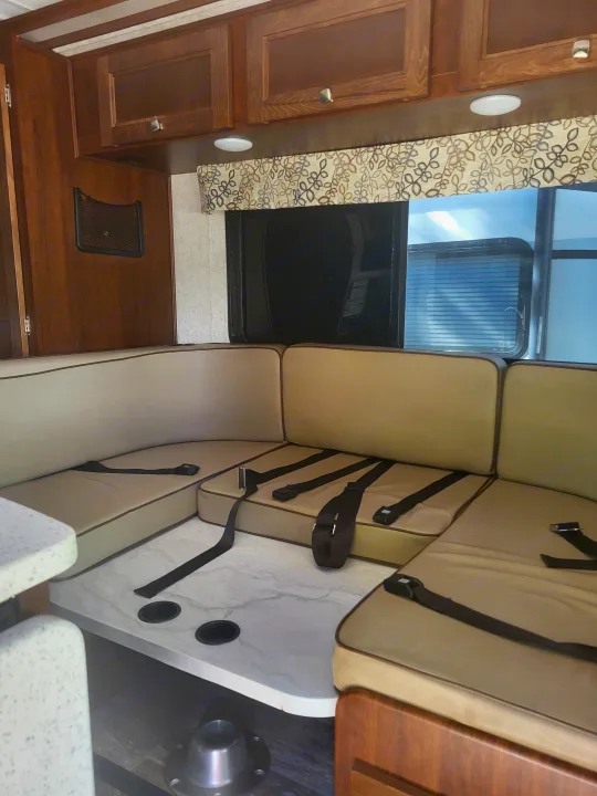 Inside this RV rental, find a light-toned dinette with seatbelts, a table with cup holders, and overhead storage.. Forester Forester Motorhome 2020