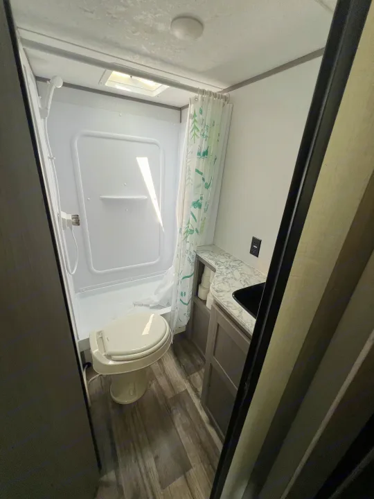 Compact RV bathroom in this rv rental, featuring a toilet, shower, and vanity with sink. Functional for your travels.. Coleman Lantern 18 2024