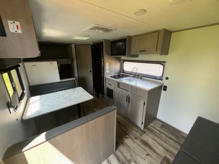 RV rental interior: a bright kitchen with stove, sink, microwave, and a comfortable dinette. Perfect for your next adventure.. Coleman Lantern 18 2024