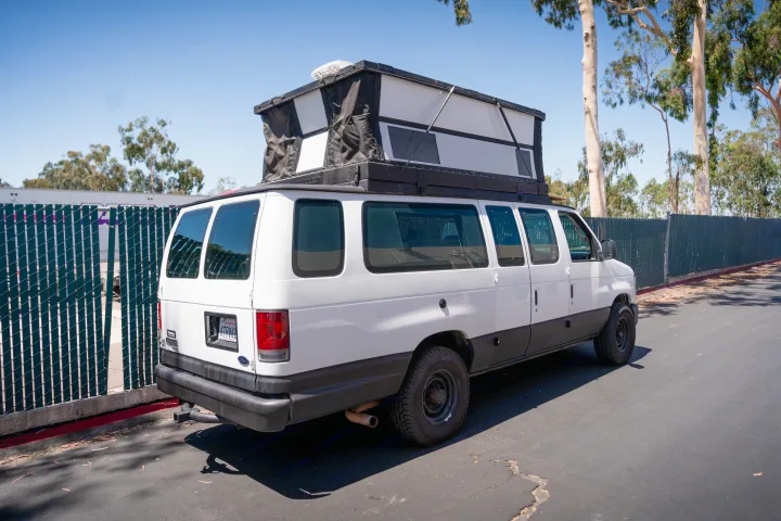 This white Ford E-series pop-top camper van, ideal for an RV rental adventure, is parked on a sunny day.. Ford Econoline 2008