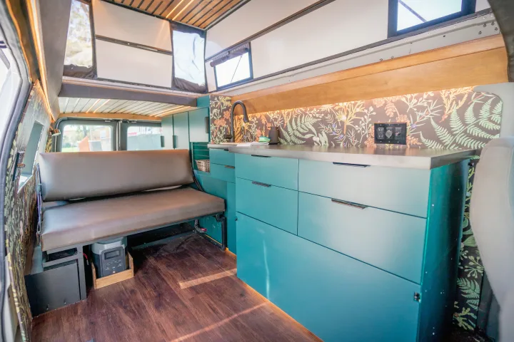 Stylish RV rental interior with teal kitchen, botanical backsplash, and comfy bench seating. Perfect for adventure!. Ford Econoline 2008