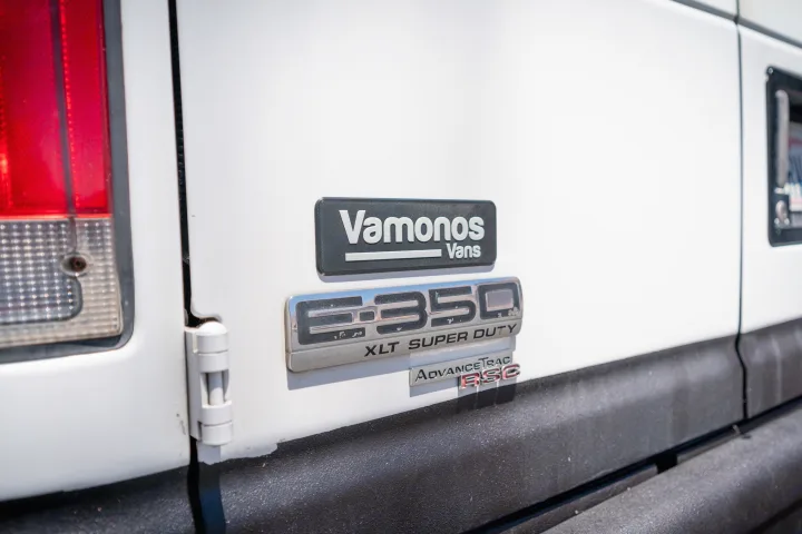 Detailed shot of an E350 Super Duty van, featuring 'Vamonos Vans' and 'AdvanceTrac RSC' badges, ideal for rv rental.. Ford Econoline 2008