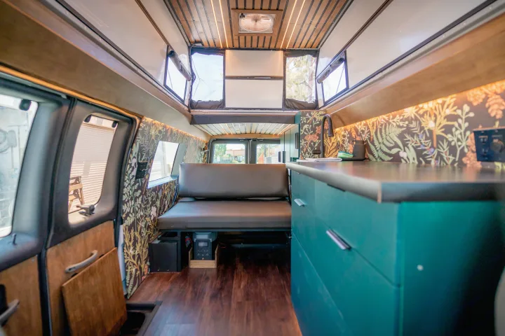 Step inside this custom RV rental: dark wood floors, teal kitchen, cozy bench, and a unique pop-top with windows.. Ford Econoline 2008