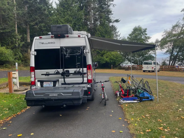 RV rental (Tellaro) parked at a campsite, awning extended, with bikes, scooters, and chairs outside.. Thor Tellaro 2022