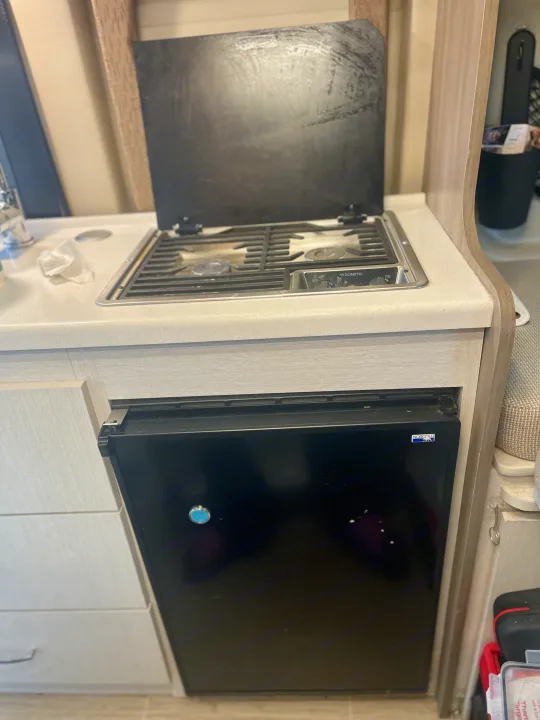 Compact RV rental kitchen with a Dometic cooktop, sink, and Norcold mini-fridge below the counter.. Thor Tellaro 2022