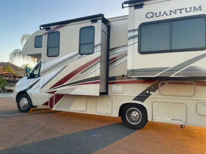 Side view of a beige Quantum RV rental, parked with slide-outs extended for more space. Ideal for your next road trip adventure.. Thor Quantum 2019