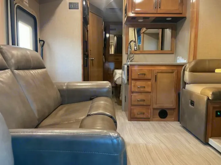 Explore this RV rental's inviting interior: leather sofa, full kitchen, and cozy dinette for travel comfort.. Thor Quantum 2019