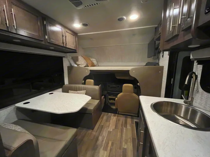 Cozy RV rental interior with dinette, overhead bunk, and kitchen. Ideal for comfortable road trips.. Entegra Odyssey SE 2025