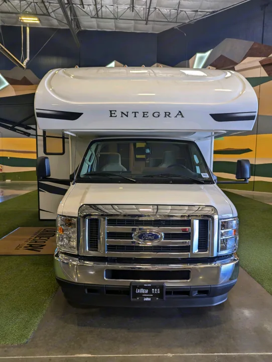Front view of a white Entegra motorhome, ideal for RV rental. Features a Ford grille and a spacious cab interior.. Entegra Odyssey SE 2025