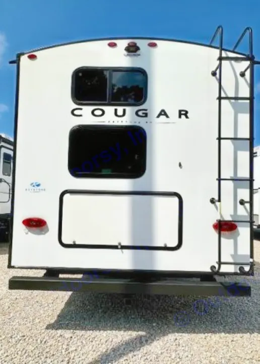 Rear exterior of a white Cougar RV rental, detailing its ladder, two windows, and a lower storage compartment.. Keystone RV Cougar 2024