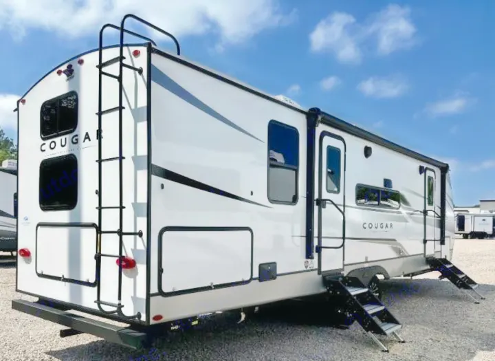 This white Cougar RV rental is ready for adventure, featuring a rear ladder, multiple windows, and dual entry steps.. Keystone RV Cougar 2024