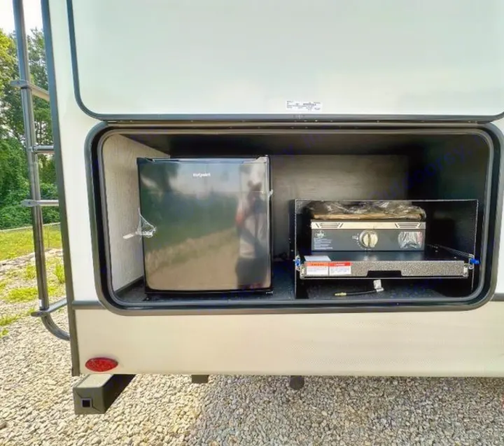 This RV rental features a convenient outdoor kitchen setup, including a mini-fridge and a camping stove for easy meal prep.. Keystone RV Cougar 2024
