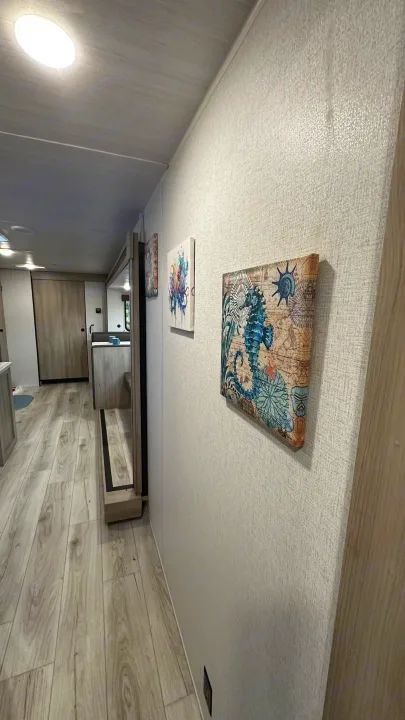 View inside an **rv rental** showing a bright hallway with light wood flooring and textured walls adorned with seahorse art.. East to West Silver Lake 3250QB 2025