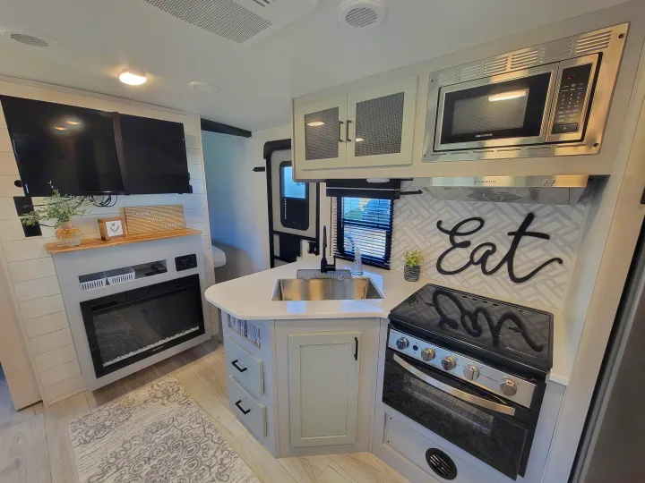 Modern RV rental interior with a cozy living area, fireplace, and full kitchen, perfect for your next adventure.. Heartland RVs North Trail 2023