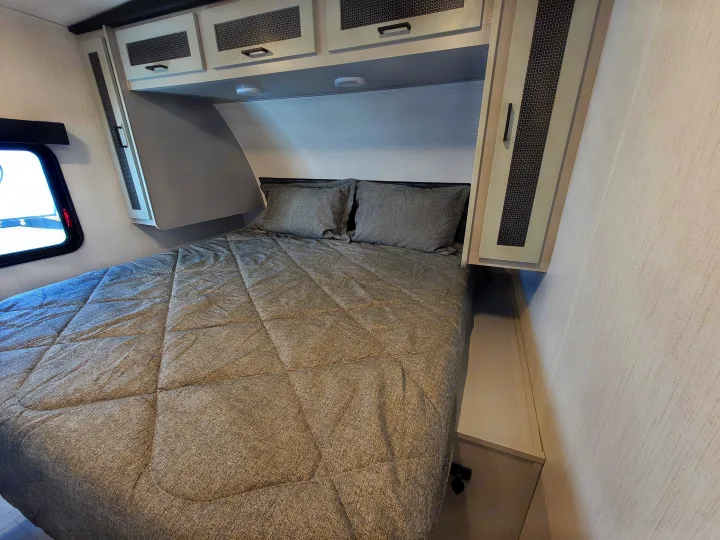 Modern RV rental bedroom featuring a cozy bed, overhead storage, and stylish finishes for your journey.. Heartland RVs North Trail 2023