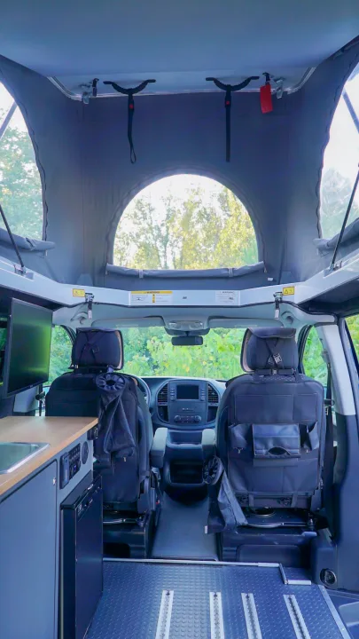 Interior of an RV rental: Pop-top roof, kitchenette, front seats, and modular floor.. Mercedes-Benz Metris 2023