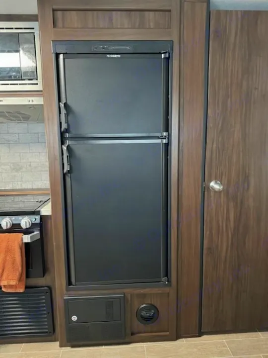 RV rental interior with Dometic fridge, stove, microwave, electrical panel, and a wooden door.. Forest River Cherokee Grey Wolf 2020