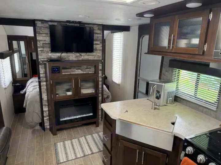 Modern RV rental interior with kitchen, living area, and bedroom. Features a fireplace, TV, and ice maker.. Forest River Cherokee Grey Wolf 2020