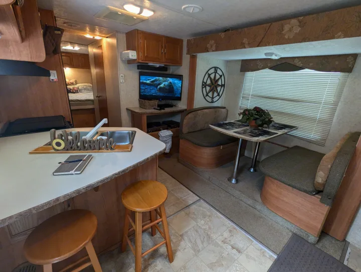 Inside a well-equipped RV rental: kitchen with stools, dining area, TV, and back bedroom.. Keystone RV Zeppelin Z-II 2006