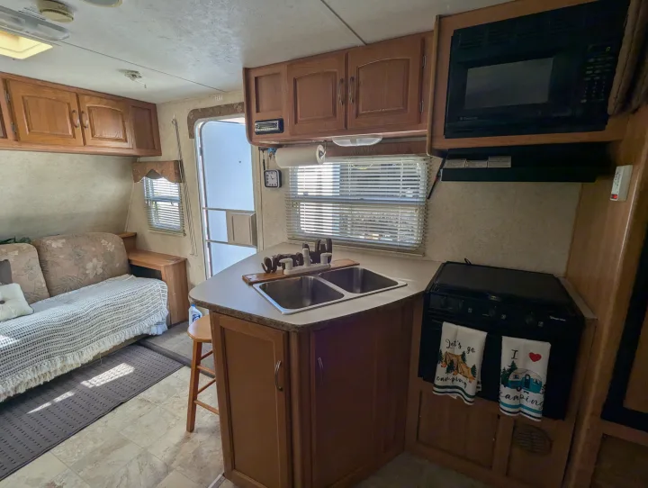 Cozy RV rental interior: kitchen with sink, stove, microwave; plus a living area with sofa/bed.. Keystone RV Zeppelin Z-II 2006