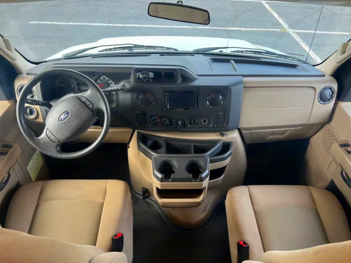 Interior of an RV rental: a clean, spacious cockpit with a beige dashboard, black steering wheel, and comfortable seats.. Winnebago Minnie Winnie 2017