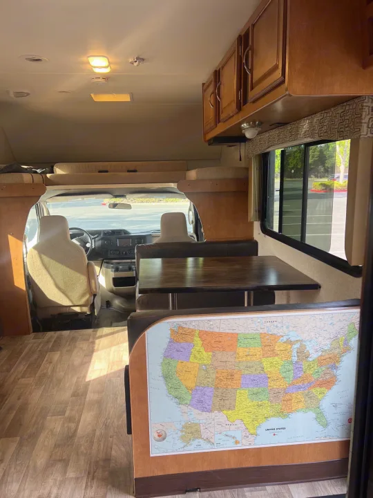 Spacious RV rental interior with dinette, front cabin, bunk, and US map on the wall. Ready for adventure!. Winnebago Minnie Winnie 2017