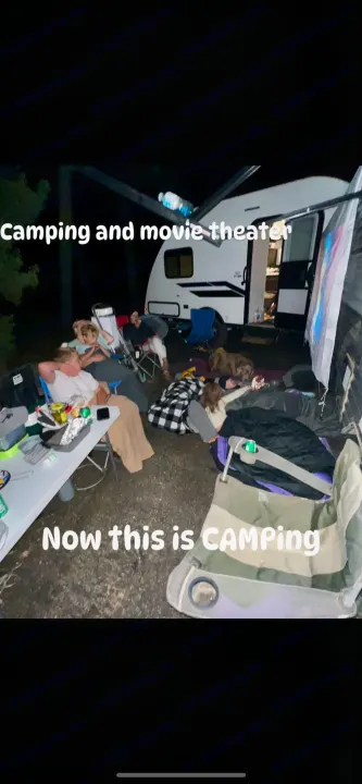 RV rental makes camping special: people & dog enjoy a projected outdoor movie night by the camper.. Dutchmen Coleman Lantern LT 2024