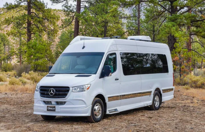 A modern white Mercedes-Benz Sprinter RV rental parked on a dirt path in a peaceful pine forest setting.. Grech RV Strada-ion 2024