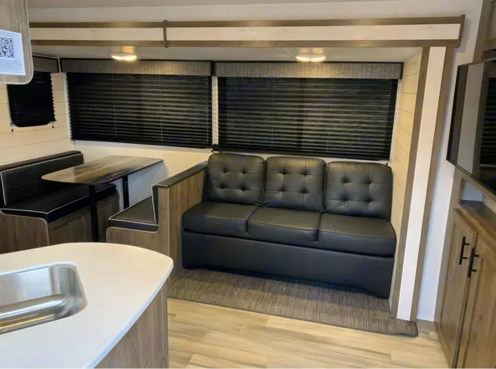 Step inside this modern RV rental! Featuring a comfortable sofa, dinette booth, and a compact kitchen area for your next adventure.. Pioneer Other 2023