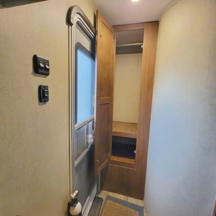 RV rental: Entryway shows door, wall-mounted light & awning controls, plus an open closet/wardrobe.. Gulf Stream Ameri-Lite 2018