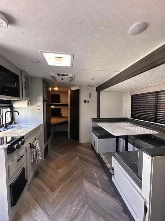 Bright rv rental interior showcases a modern kitchen, comfortable dining area with a table, and bunk beds in the rear.. Forest River Salem FSX Plantium 2022