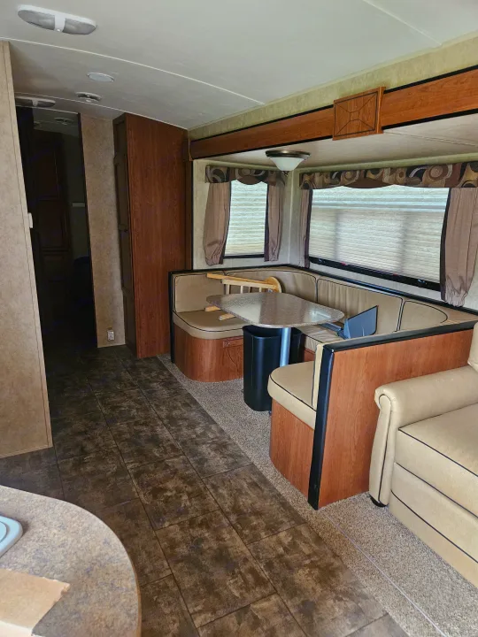 Step into this clean RV rental interior, featuring a comfortable U-shaped dinette, large windows, and practical flooring.. Dutchmen Aerolite 2013