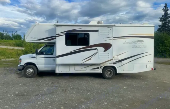 White Fleetwood Jamboree Searcher **rv rental** parked on gravel. This motorhome is ready for your next travel adventure.. Jamboree Searcher 2014