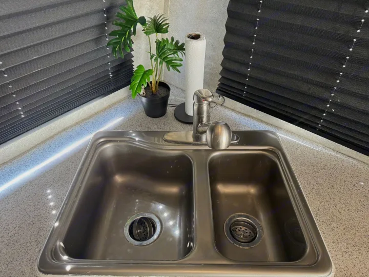 RV rental kitchen sink and counter with paper towels, a plant, and window blinds visible in a corner setup.. Weekend Warrior 1800sxfk 2009