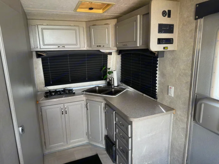 RV rental kitchen interior: light gray cabinets, dual sink, gas stove, & control panel. A functional space for road trips.. Weekend Warrior 1800sxfk 2009