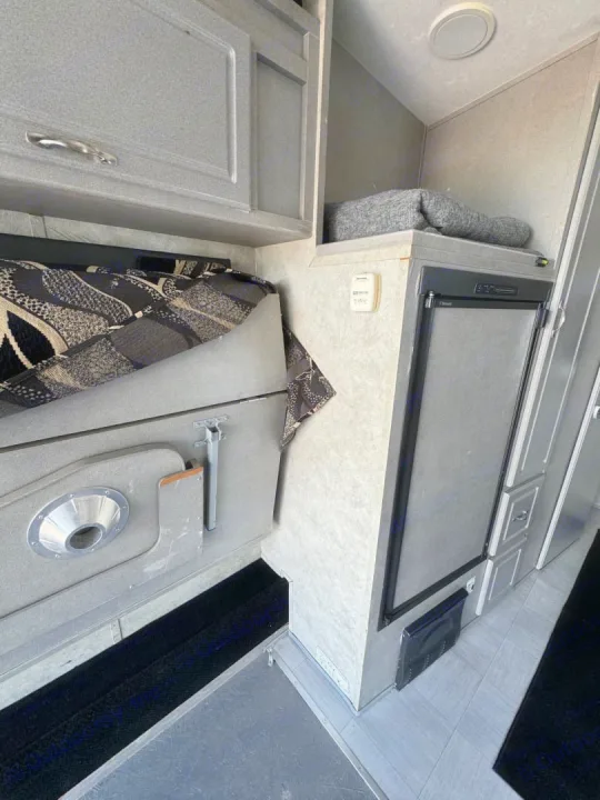 RV rental interior: Compact living space with a small fridge, overhead cabinets, and convertible seating/bed.. Weekend Warrior 1800sxfk 2009