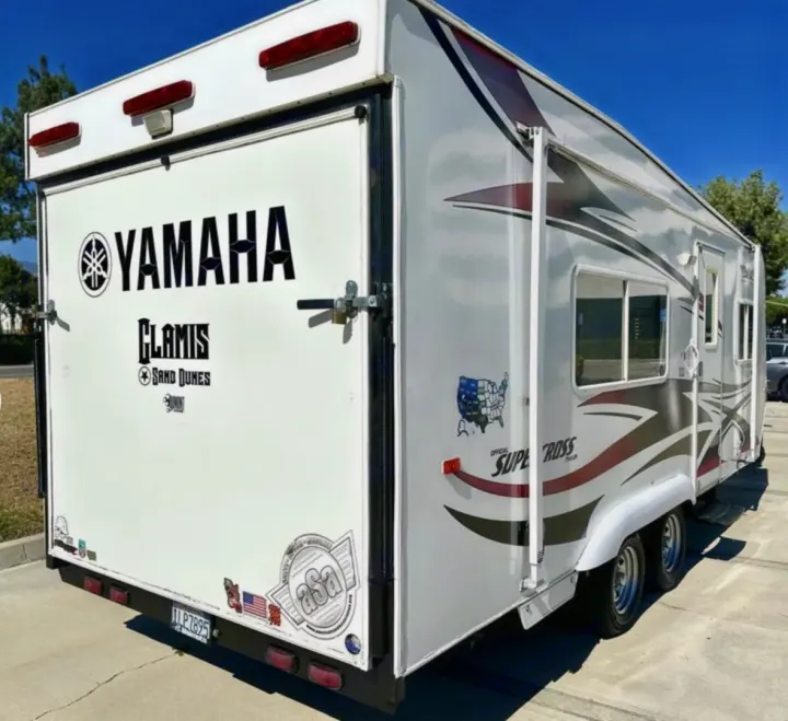 White toy hauler RV rental featuring Yamaha, Glamis Sand Dunes, and Supercross decals. Rear ramp door, windows, and dual axles.. Weekend Warrior 1800sxfk 2009