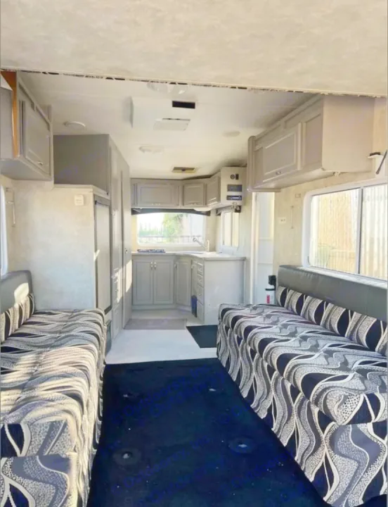 RV rental interior: A full kitchen at the rear, flanked by two long patterned sofas. Features gray cabinetry & dark floor.. Weekend Warrior 1800sxfk 2009