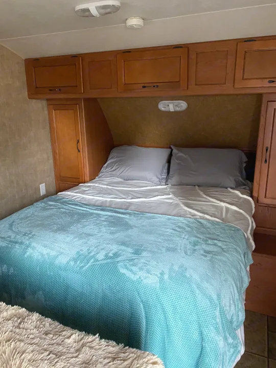 Cozy RV rental bedroom with overhead cabinets, a comfortable bed, and compact design.. Forest River Cherokee Grey Wolf 2012
