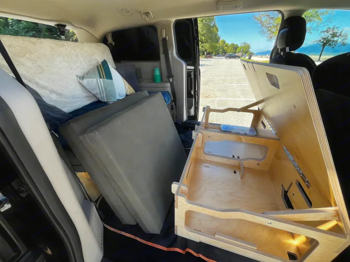 Minivan car camping setup with bed & modular wooden kitchen/storage unit inside, perfect for an RV rental.. Dodge Grand Caravan 2014